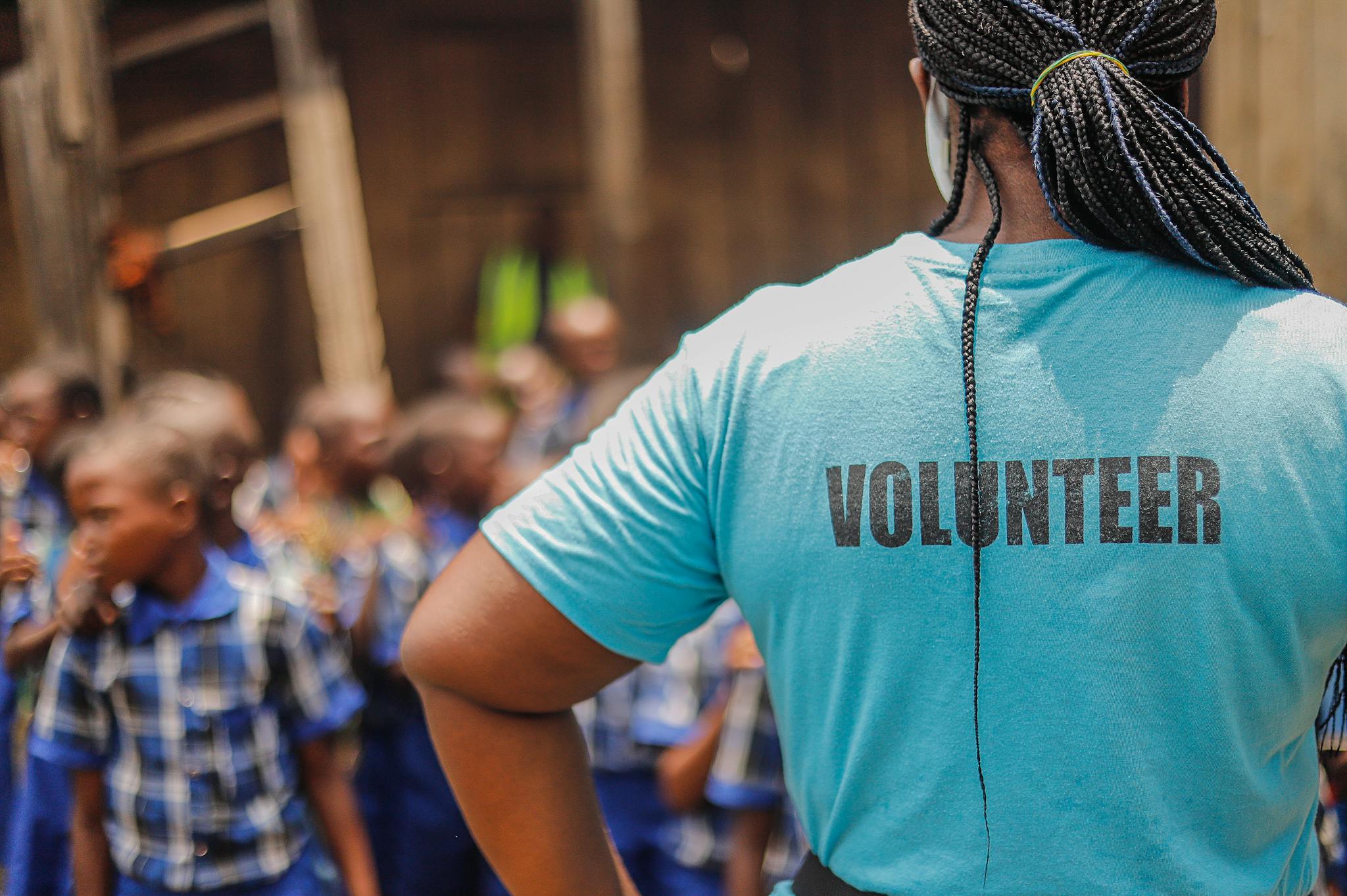A volunteer interacts with children in a village school setting, fostering community support and development.